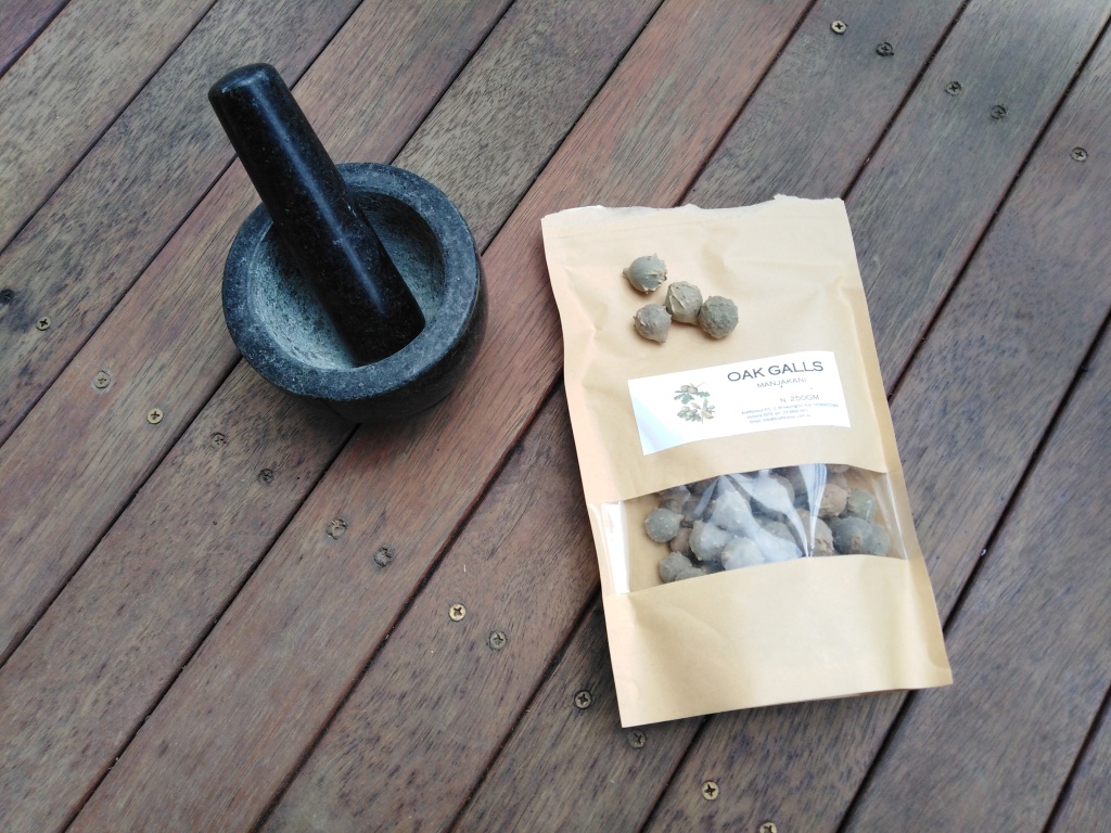 mortar and pestle next to paper bag filled with oak galls